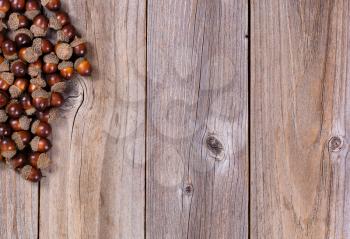 Overhead view of seasonal autumn acorn decorations, upper left corner, on rustic wooden boards. 