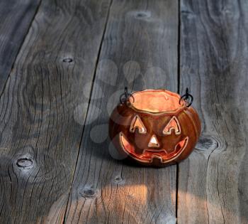 Ceramic glowing pumpkin decoration on rustic wooden boards