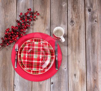 Overhead view of a festive Christmas dinner setting with red berry decorations on top of rustic wood