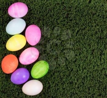 Colorful Easter egg decorations forming left hand border on green grass.  