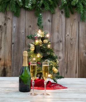 Holiday champagne for the winter season with Christmas tree and rustic wood in background 