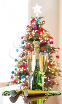 Happy New Year Celebration with golden champagne and bright Christmas tree in background