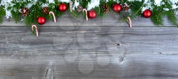 Overhead view of snow covered fir Christmas tree branches with decorations on weathered wood  