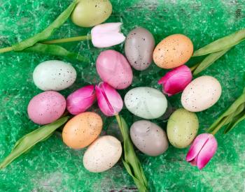 colorful eggs and tulips on artificial green grass for Easter Background 