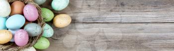 colorful eggs in nest on rustic wooden boards for Easter Background 