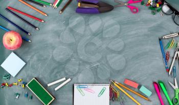 Back to school concept with green erased chalkboard and a variety of student supplies in circle border 