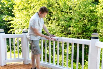 Mature man hammering nails in railing of outdoor deck