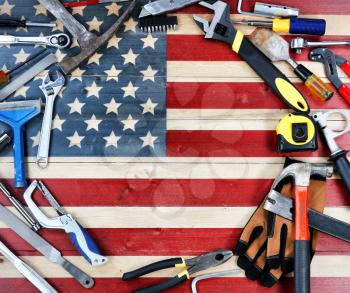 Labor Day concept with circle border of industrial worker tools over distressed United States wooden flag background 