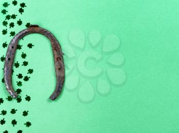 Saint Patricks Day with border of shamrocks and rusty horseshoe on green background with copy space 