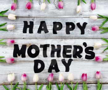 Happy Mothers Day holiday concept with pink tulip box shaped border on white rustic wood plus large letter text ready for use 