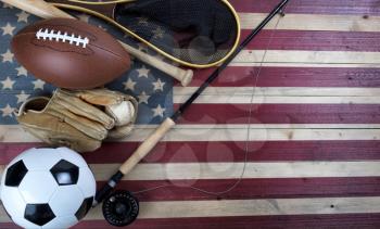 Various sport equipment for baseball, football, soccer and fishing on vintage wooden USA flag 