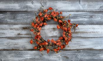 Seasonal autumn wreath with orange bell flowers on white rustic wooden background 