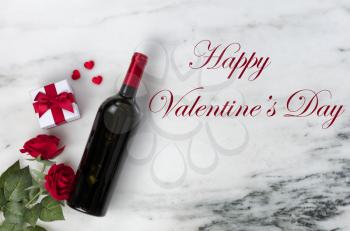 Happy Valentines Day with lovely rose flowers and red wine bottle plus giftbox on natural marble stone including text message 