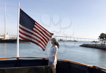 Woman holding cloth US flag while riding in boat on water 