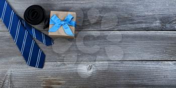 Fathers day concept with blue dress tie, belt and a gift box on rustic wooden background in flat lay format