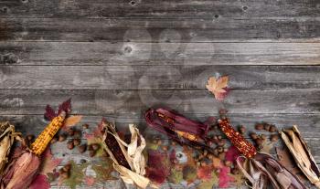 Autumn border with faded leaves, acorn and corn on vintage wooden planks 