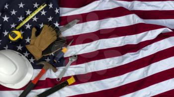 American flag with an assortment of work tools plus work gloves for US Labor Day holiday concept background 