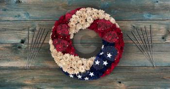 Wreath with United States national colors of red, white and blue with stars plus sparklers on faded blue wooden planks for happy memorial or Independence Day background concept 