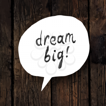 Dream big lettering in speech bubble on wooden texture