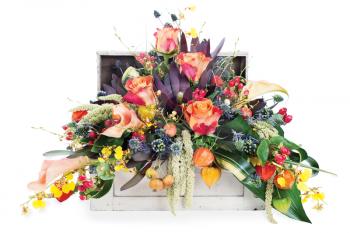 colorful floral arrangement of roses, lilies, freesia and irises in a wooden chest, isolated on white background