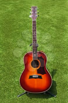 Acoustic guitar on background of green grass.
