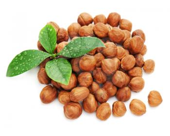 Heap of fresh shelled hazelnuts with green leaves isolated on white background. Closeup.