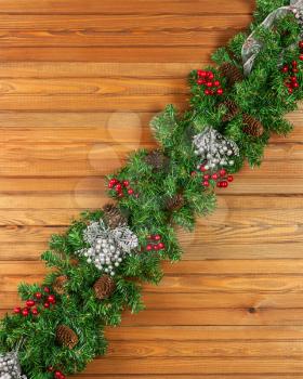 Garland with Christmas ornaments and pine cones on old wooden background.