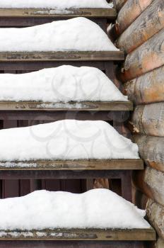 Powdery snow covered old wooden stairs. Abstract winter background composition.