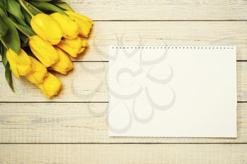 Fresh yellow tulips with easter greeting card on wooden background. Top view with copy space. Photo with retro filter effect.
