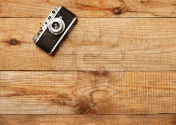 Vintage, very old film camera on brown wooden background and space for text.
