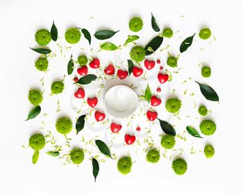 Cup for coffee or tea with pattern with petals of chrysanthemum flowers, ficus leaves, hearts and ripe rowan on white background. Overhead view. Flat lay.
