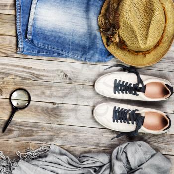 Set of travel items including shoes, scarf, jeans, magnifying glass and straw hat. Overhead view. Flat lay.