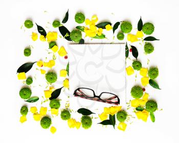 Glasses and paper with pattern from petals of roses and chrysanthemum flowers, ficus leaves and ripe rowan on white background. Overhead view. Flat lay.
