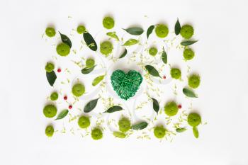 Heart with pattern from petals of chrysanthemum flowers, ficus leaves and ripe rowan on white background. Overhead view. Flat lay.
