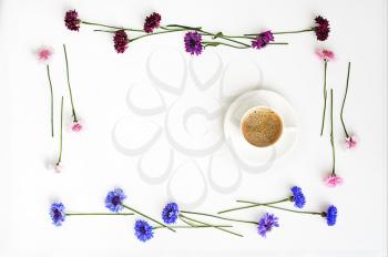 Cup of coffee with pattern from petals of wildflowers on white background. Overhead view. Flat lay.
