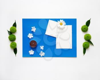 Blue paper with candles and decoration of chrysanthemum flowers and ficus leaves on white background. Overhead view. Flat lay.