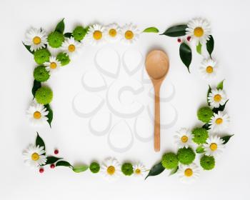 Wooden ladle and space for your text or product with decoration of chrysanthemum flowers and ficus leaves on white background. Overhead view. Flat lay.