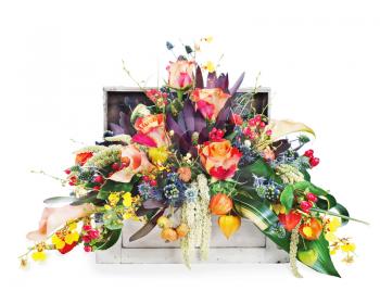 Colorful floral arrangement of roses, lilies, freesia and irises in a wooden chest isolated on white background.