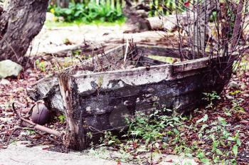 Last place of old broken boat in autumn garden. Vintage style.