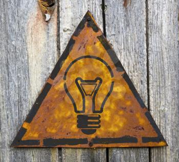 Royalty Free Photo of a Light Bulb on a Rusty Sign on a Wooden Wall