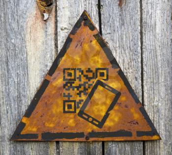 Royalty Free Photo of a QR Code and Cellphone on a Rusty Sign Against a Wooden Wall