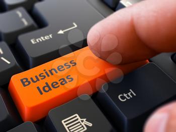 Business Ideas Button. Male Finger Clicks on Orange Button on Black Keyboard. Closeup View. Blurred Background.
