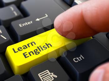 Learn English Button. Male Finger Clicks on Yellow Button on Black Keyboard. Closeup View. Blurred Background.