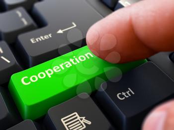 Cooperation Button. Male Finger Clicks on Green Button on Black Keyboard. Closeup View. Blurred Background.