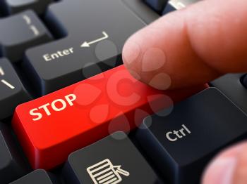 Stop Button. Male Finger Clicks on Red Button on Black Keyboard. Closeup View. Blurred Background.