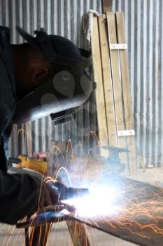 Royalty Free Photo of a Man Welding a Piece of Iron a Work Table