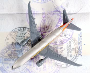 Toy plane over an open passport showing travel seals