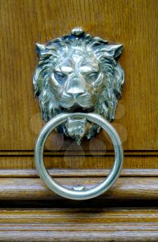 Close up of a silver lion head door knock  on a wooden heavy door in Paris, France                            