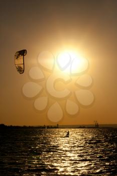 Sepia-toned photo of the evening sun and the kite-surfer sliding on the water