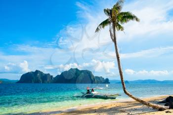 Tropical landscape with mountain islands, palm tree and lonely boat